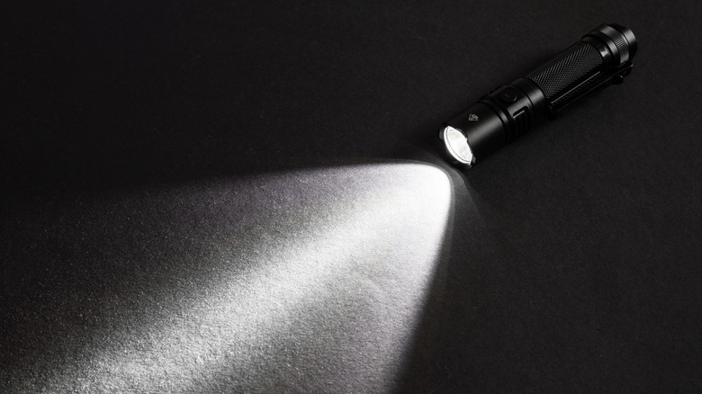 A flashlight turned on against a black surface.