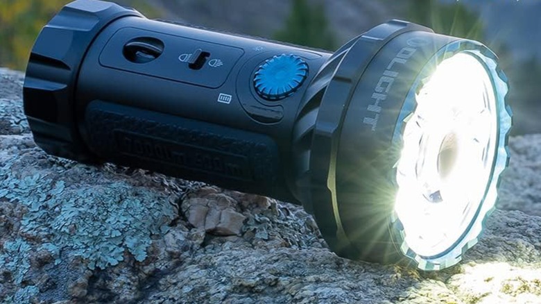 An Olight Marauder Mini flashlight on a rock.