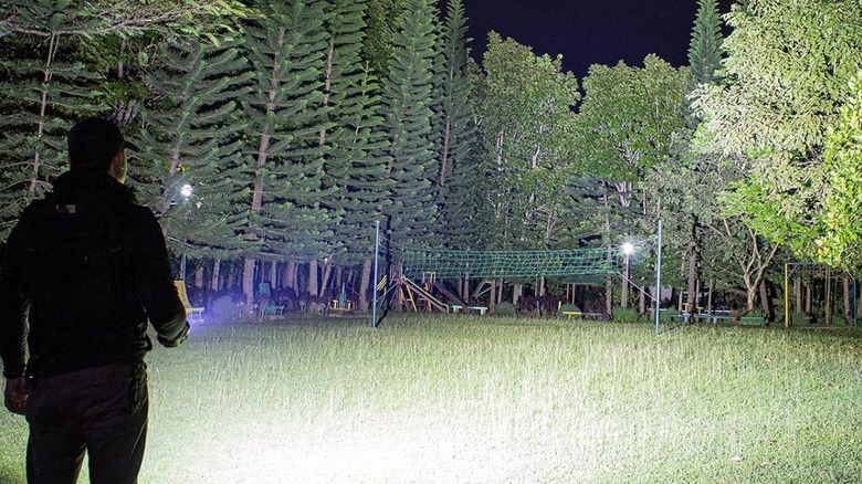 man using sofirn Q8 Plus Flashlight in backyard