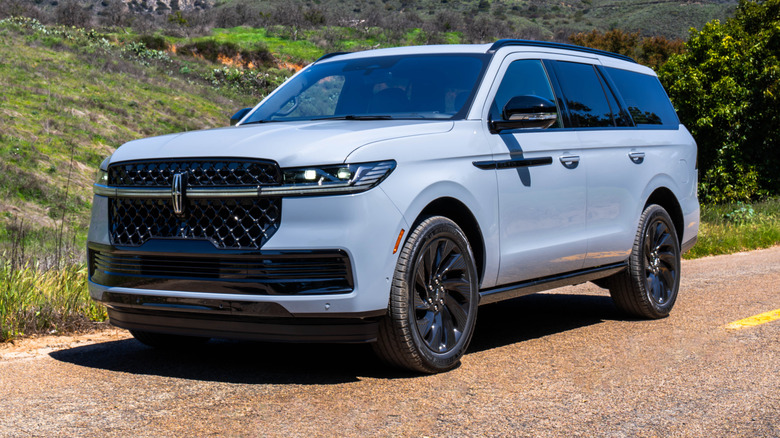 Front 3/4 static shot of a 2025 Lincoln Navigator Reserve with trees and mountains in the background