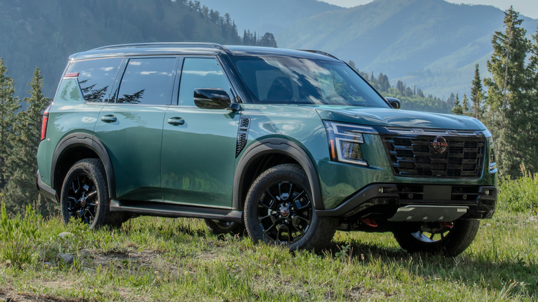 2025 Nissan Armada PRO-4X parked on a grassy field  with trees and mountains in the background