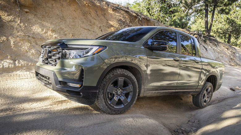 Front 3/4 view of green Honda Ridgeline pickup on off-road trail.
