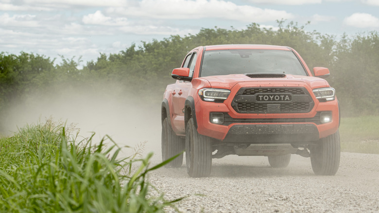 Front view of orange 2023 Toyota Tacoma on dirt trail.