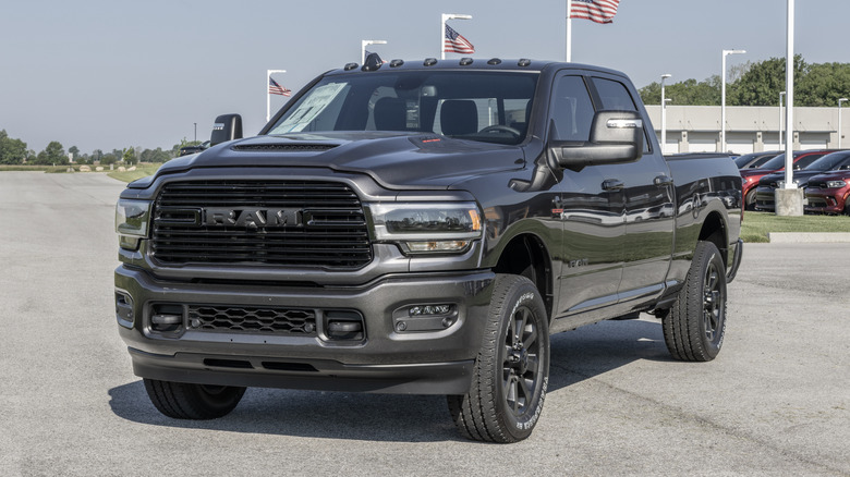 Front 3/4 view of gray Ram 2500 pickup parked in front of car dealership.