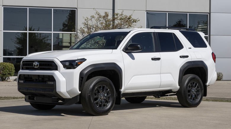 A white new Toyota 4Runner parked in front of a dealership.