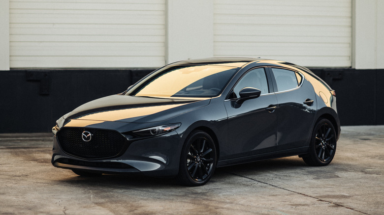 Front 3/4 view of gray Mazda3 hatchback parked at loading dock.