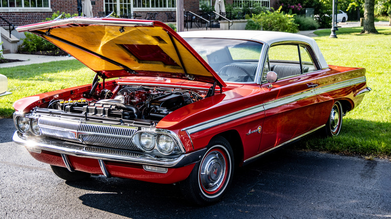 Red 1962 Oldsmobile Jetfire coupe seen from front left with hood open to reveal innovative turbocharged engine