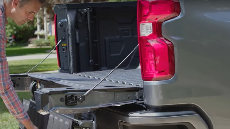 A man lowers the Multi-Flex Tailgate of a silver 2022 Chevy Silverado pickup