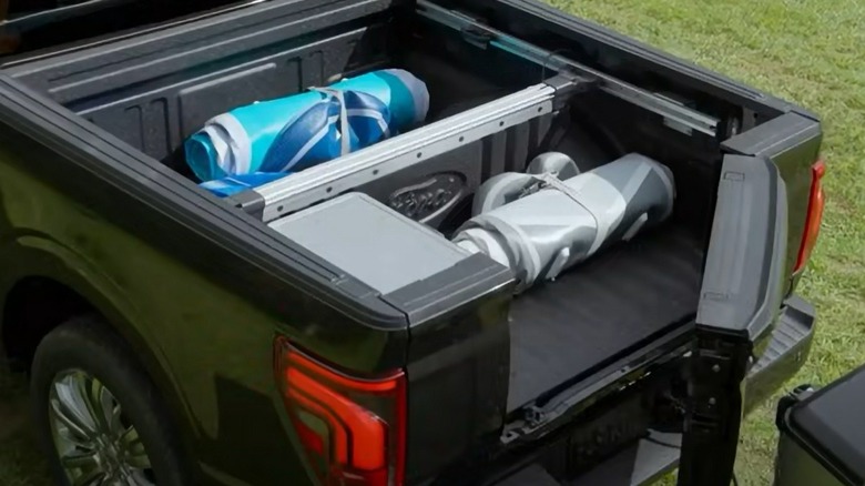 Black Ford F-150 pickup with Pro Access tailgate open demonstrating how it avoids hitting the trailer