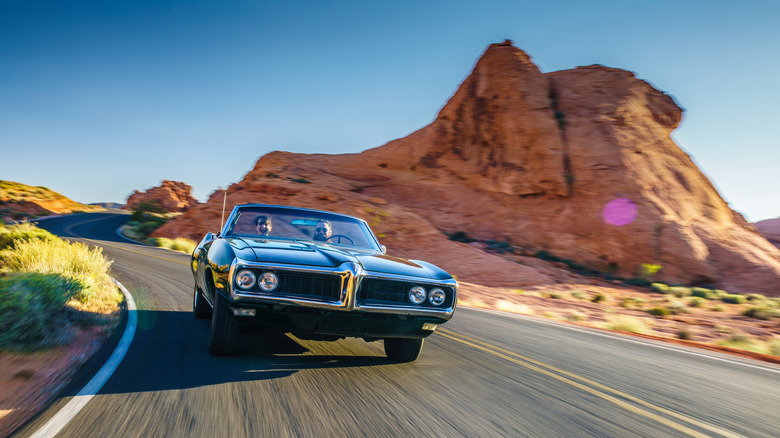 vintage convertible driving in desert landscape