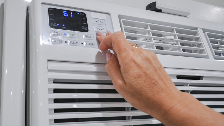 A person pressing buttons on an air conditioner.