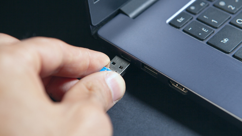 Person plugging a small USB flash drive to a laptop