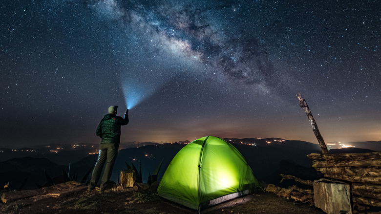 camper pointing flashlight at sky