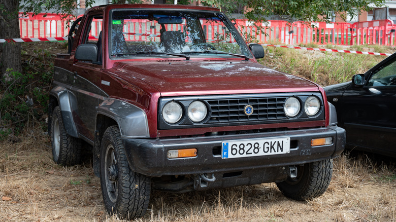 A dark red Bertone Freeclimber sitting on grass underneath a tree
