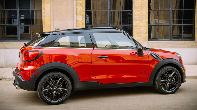 A bright red MINI Paceman parked in front of a stone building