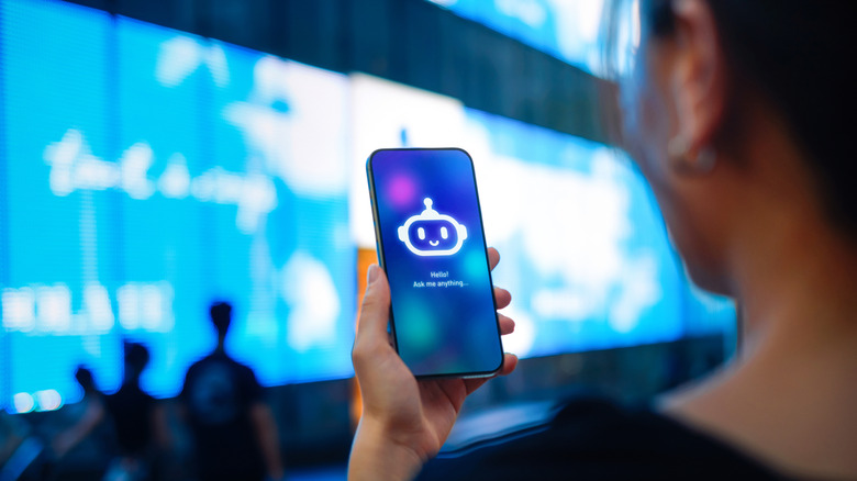 Person facing a smartphone screen displaying a robot icon