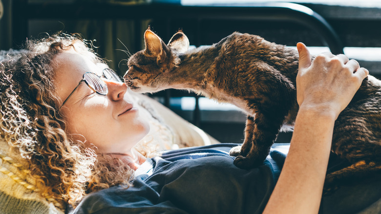 Woman lying on back with cat on her chest
