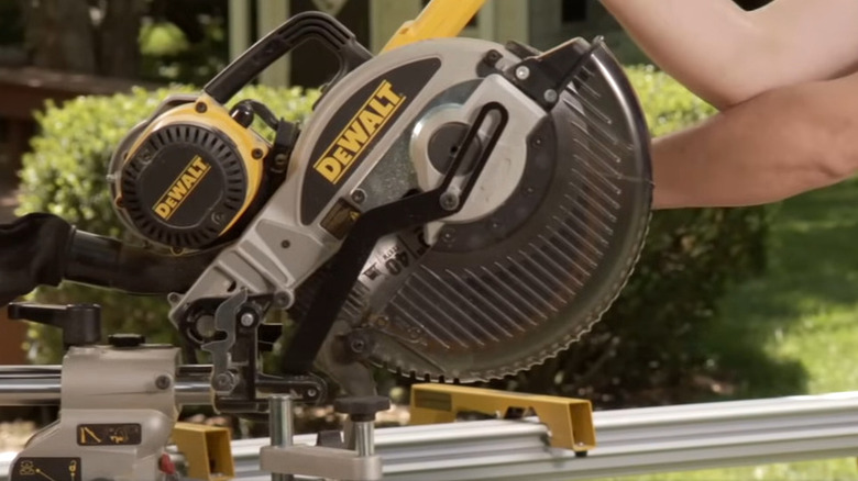 Person putting their arms across a miter saw blade