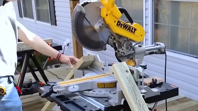 A miter saw with a cut piece of lumber fallen on either side