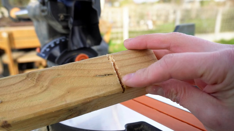 Person pointing at a frayed cut in a piece of wood