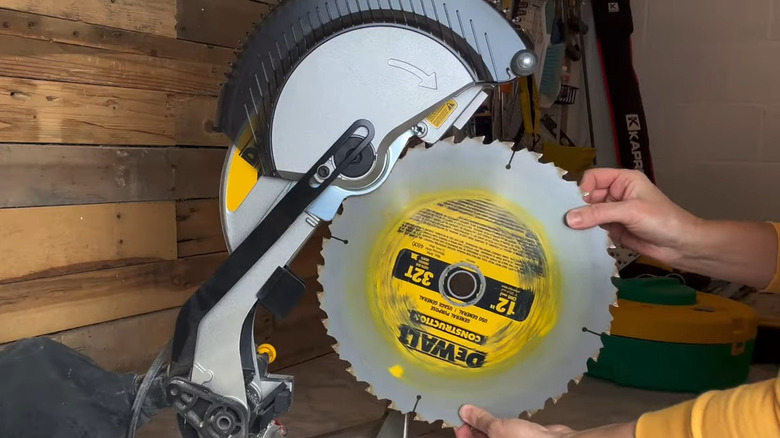 Person swapping out a blade on a miter saw in a workshop