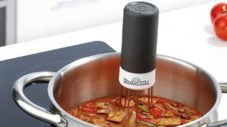 Robotic pot stirrer in a pot of soup on a stovetop