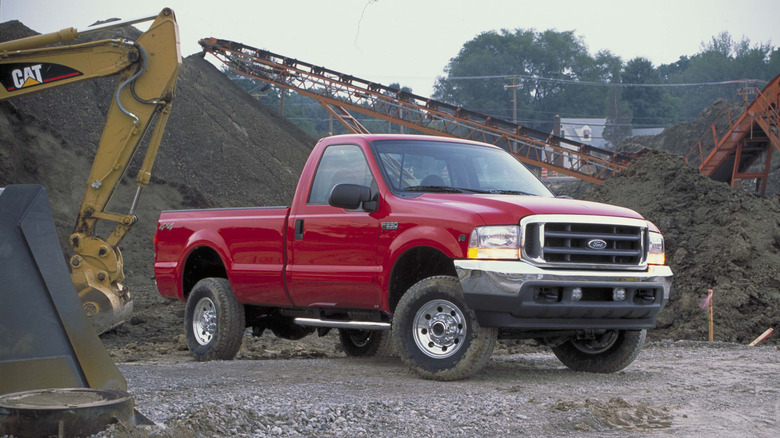 A red 2003 Ford F-350 pickup on a work site with heavy machinery..