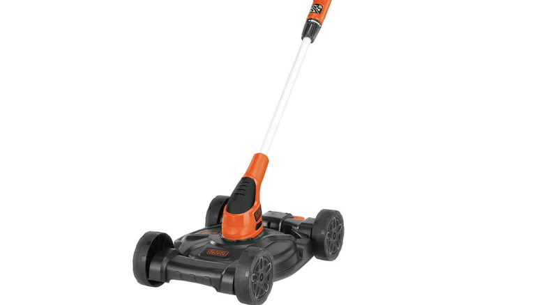 A small black and orange lawn mower with a large handle on a white background