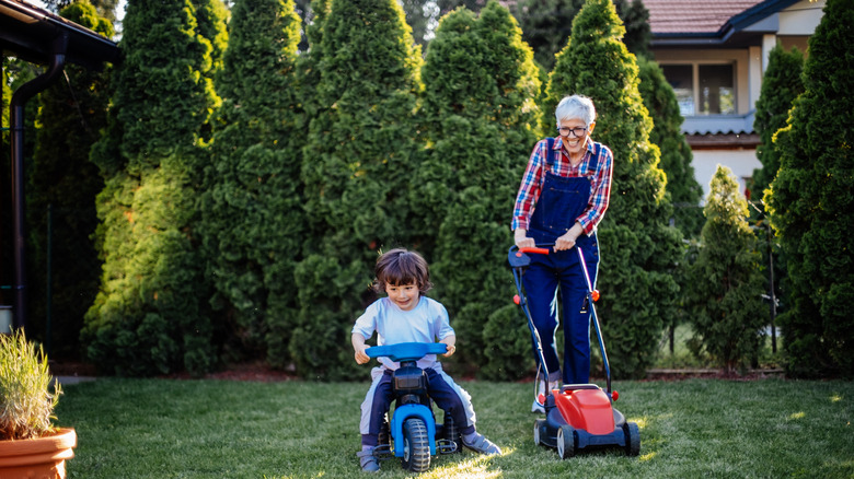 An adult and a child mowing the lawn on a sunny day on a bright lawn