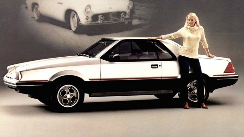 Side view of a white Ford EXP with model in studio setting with vintage Thunderbird in background