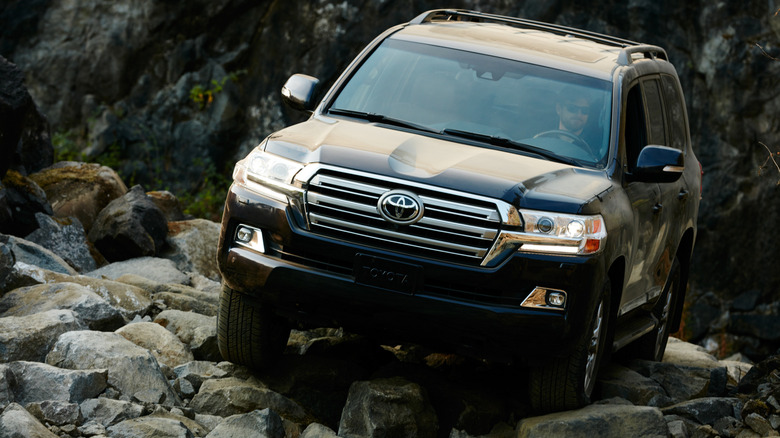 A black 2016 Toyota Land Cruiser from the LC200 generation crawling over rocks offroad.