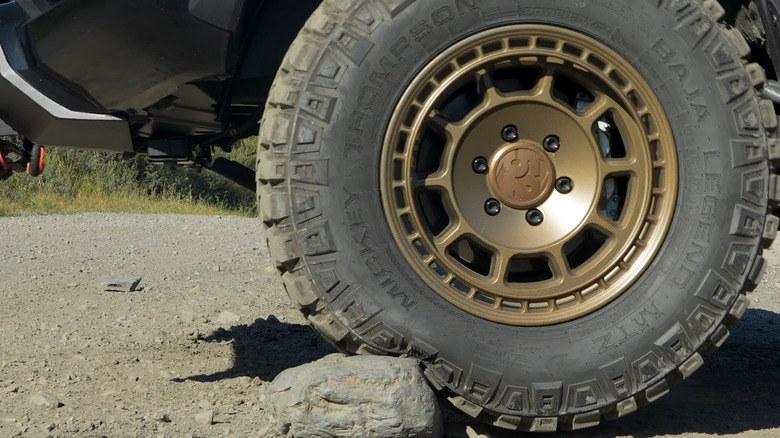 Large mud-focused off-roading tires going over a rock and absorbing it into themselves after being aired down to 20 PSI.