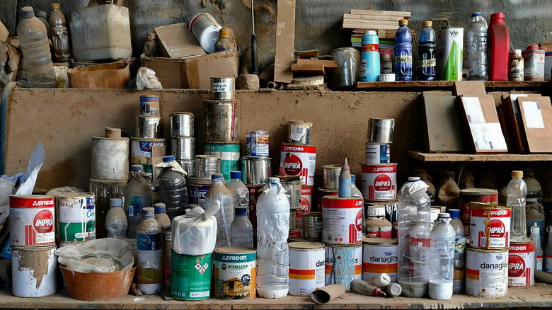 A shelf in a workshop crammed with paint tins and other inflammable liquids