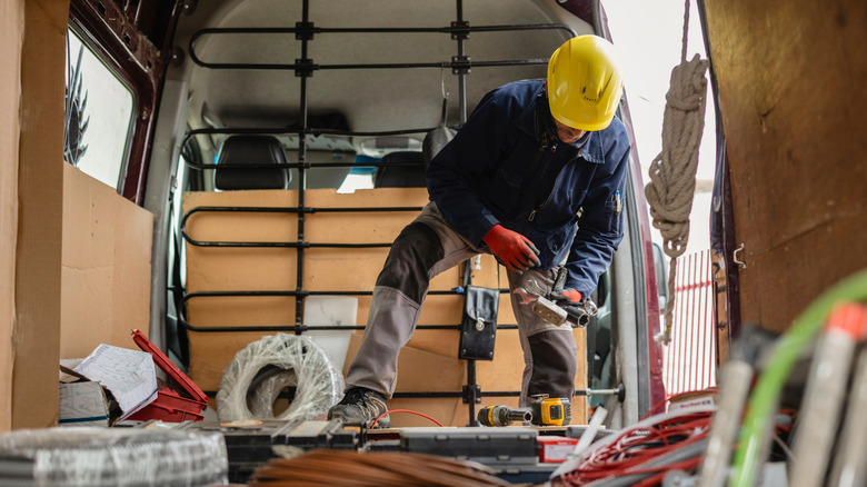 Worker in vehicle preparing materials and equipment.