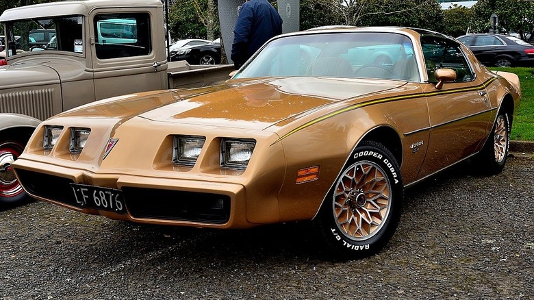 A mustard yellow 1981 Pontiac Firebird parked.