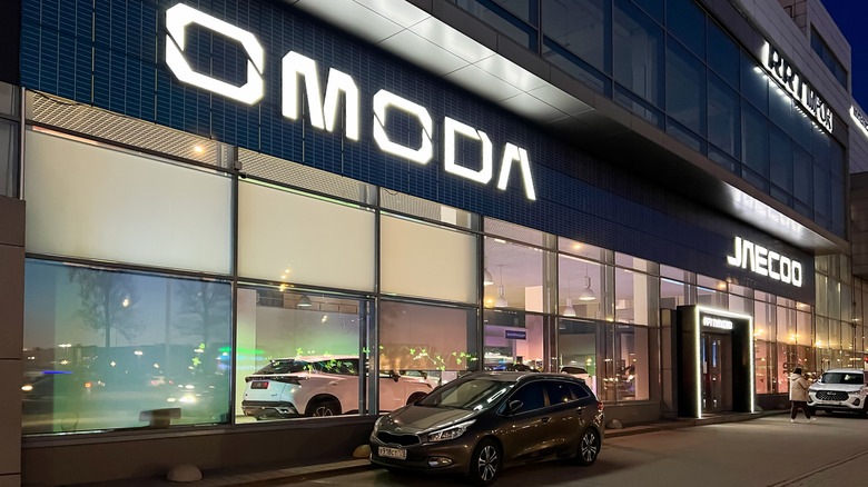 An Omoda car dealership with a light-up sign seen glowing at night