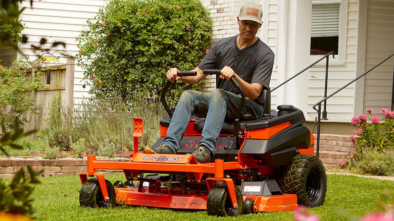 Person riding on a Bad Boy Magnum in a small yard with a house in the background