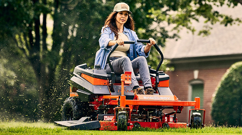 Person riding a Bad Boy MZ Rambler lawn mower with grass coming from the rear