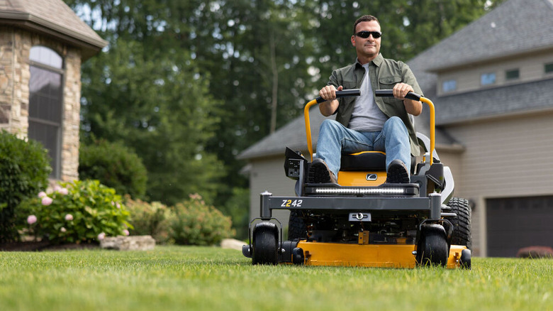 Person riding a Cub Cadet Z2 42 lawn mower on grass with a house behind