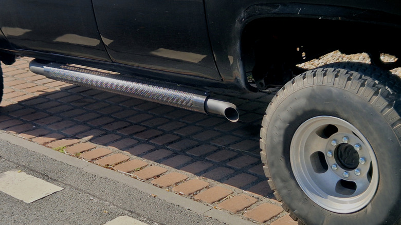 Close up view of side pipe exhaust on lifted vintage pickup truck.