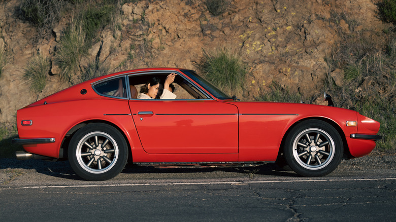 A side profile view of a vintage 1980s red car on the road.