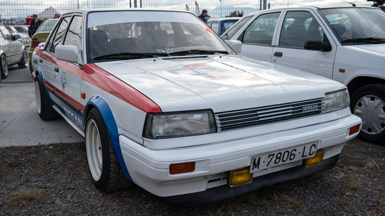A modified 1980s Nissan T12 sedan parked near other cars.