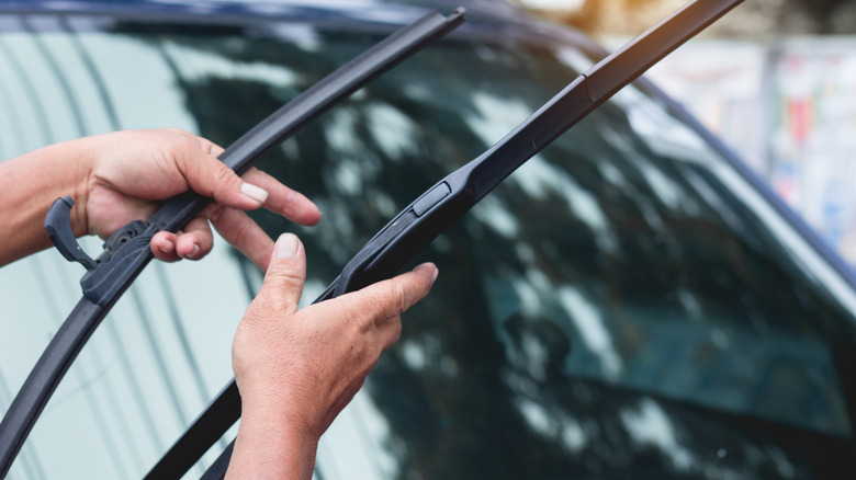 Close-up of hand replacing two windshield wiper blades