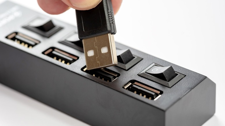 Person putting USB into black USB-A hub with switches