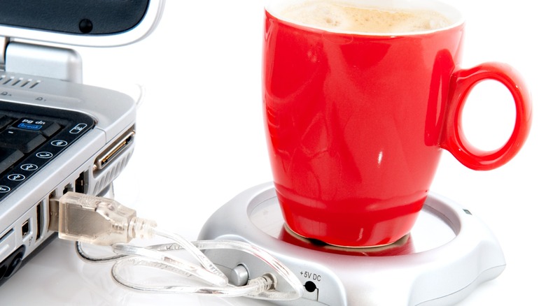 White USB mug warmer connected to laptop with red cup on it