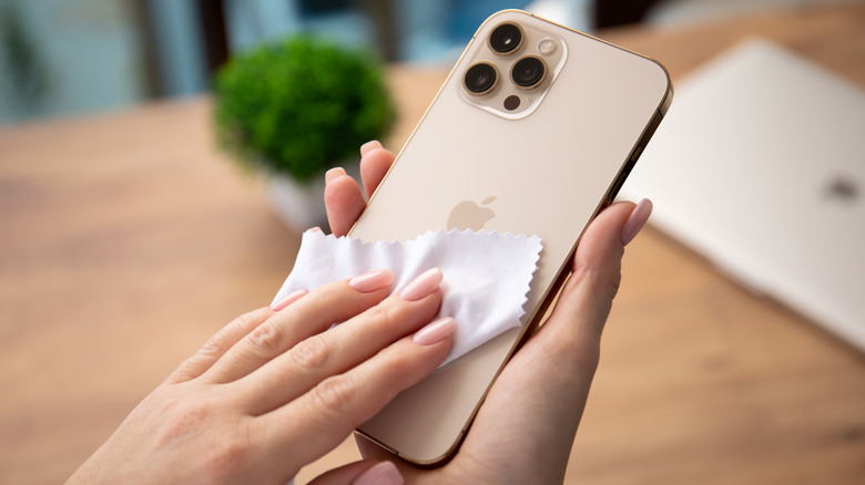 manicured hands cleaning an iPhone