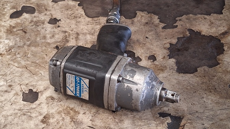 An old, damaged air impact wrench on the floor.
