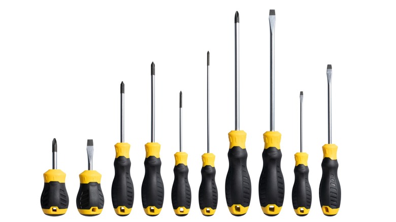 Many screwdrivers of multiple sizes, all with a yellow and black handle.