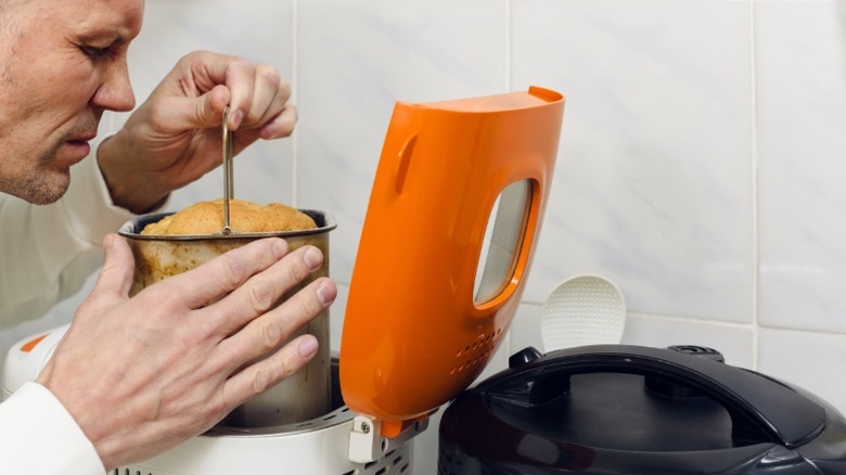 A man smelling freshly baked bread from a bread maker machine