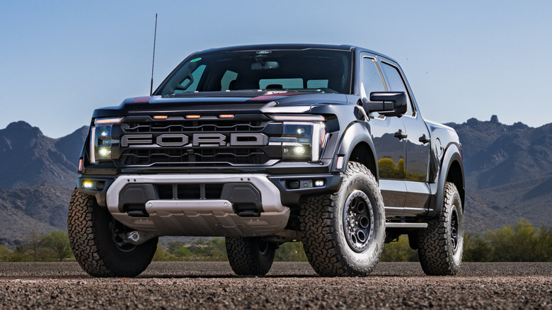 A black 2025 Ford F-150 Raptor parked in front of a mountain range.